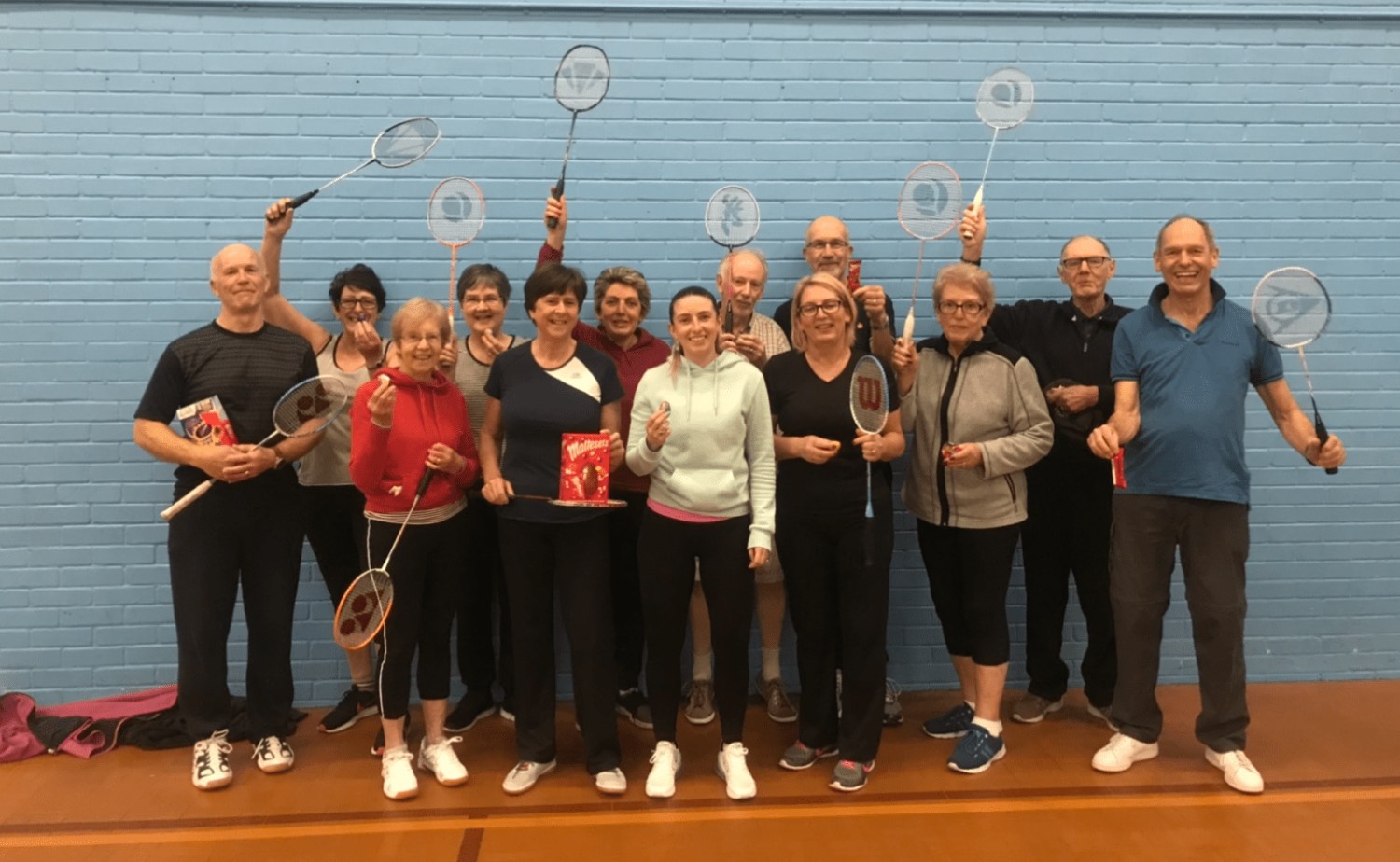 A cheerful group of adult players holding rackets aloft after a Dorset session